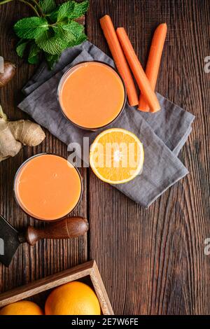 Boisson nourrissante pour le petit déjeuner, carottes fraîches, jus d'orange et de gingembre sur fond de bois rustique Banque D'Images