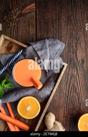 Boisson nourrissante pour le petit déjeuner, carottes fraîches, jus d'orange et de gingembre sur fond de bois rustique Banque D'Images