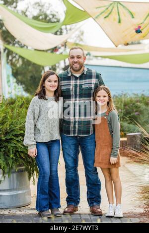 Un beau-père avec ses deux filles debout à l'extérieur un parc du centre-ville Banque D'Images