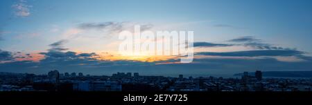 Tôt le matin ciel d'hiver juste avant le lever du soleil sur la petite ville de bord de mer. L'aube dorée s'illumine dans le ciel au-dessus d'une ville en sommeil. Paysage panoramique Banque D'Images