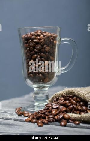 Grains de café. Versé dans un gobelet en verre et un sac de lin. Gros plan. Banque D'Images