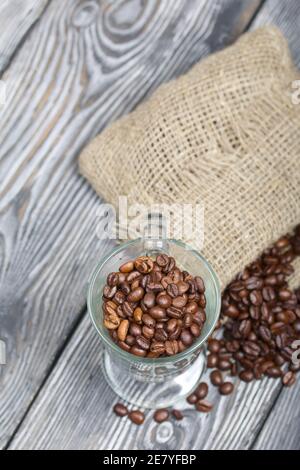 Grains de café. Versé dans un gobelet en verre et un sac de lin. Gros plan. Banque D'Images