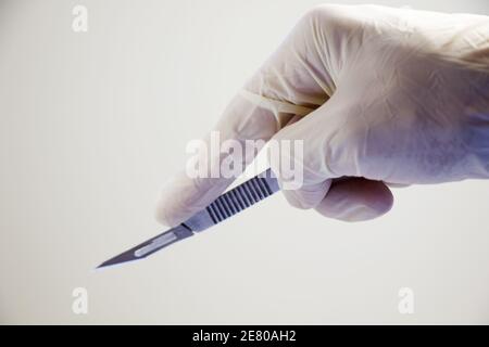 Tir isolé d'un couteau chirurgical dans la main des médecins gants blancs Banque D'Images