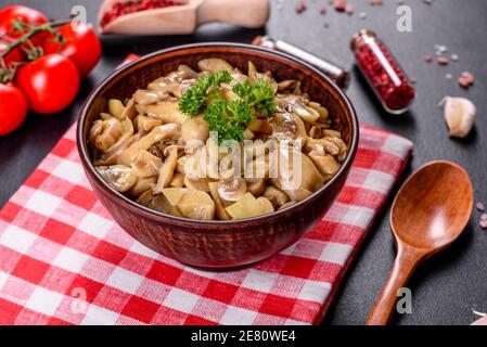Champignons frais délicieux épicés en conserve avec épices et herbes plats en céramique sur fond de béton foncé Banque D'Images