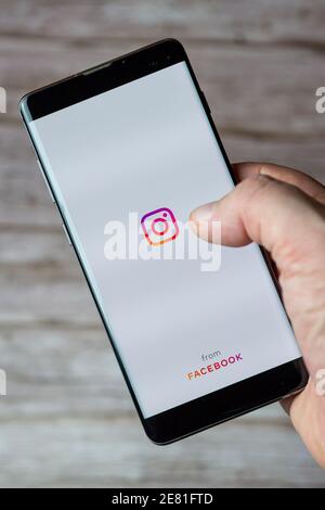 Une main tenant un téléphone portable ou un téléphone cellulaire avec L'application Instagram s'ouvre à l'écran Banque D'Images