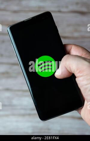 Une main tenant un téléphone portable ou un téléphone cellulaire avec L'application musicale Spotify s'ouvre à l'écran Banque D'Images