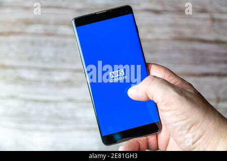 Une main tenant un téléphone portable ou un téléphone cellulaire avec L'application NHS Covid-19 TRACK and trace s'ouvre à l'écran Banque D'Images