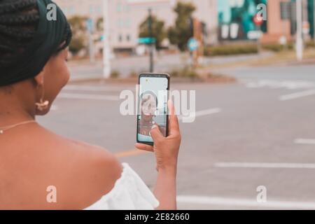 Femme africaine souriante prenant un selfie avec un smartphone Banque D'Images
