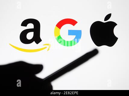 Dans cette photo, illustration d'une silhouette de main tenant un téléphone mobile vu devant les logos Google, Amazon et Apple. Banque D'Images