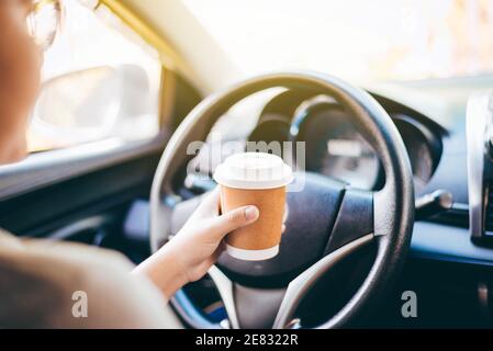 main de femme tenant une tasse de café à emporter, elle conduit le matin. Banque D'Images