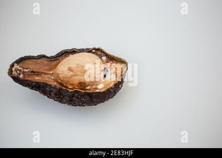 La moitié de l'avocat pourri malsain sur fond clair. Mauvaise coupe d'avocat ouverte. Avocat moisie Banque D'Images