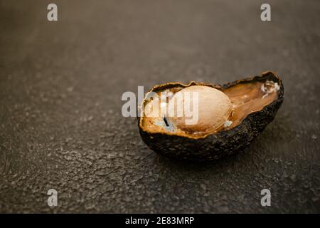 La moitié de l'avocat pourri malsain gâté sur fond sombre. Mauvaise coupe d'avocat ouverte. Avocat moisie. Copier l'espace. Banque D'Images