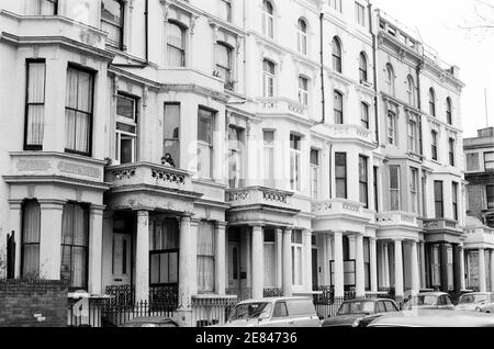 Royaume-Uni, West London, Notting Hill, 1973. Les grandes maisons de quatre étages en ruine et en ruine commencent à être restaurées et redécorées. Logement comprenant la place no.36 Powis, Talbot Road à droite. Les enfants regardent d'un balcon sur une maison qui a besoin d'entretien. Banque D'Images