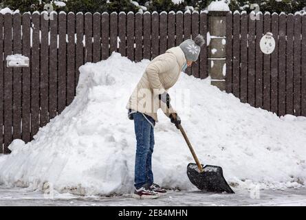 Riga, Lettonie. 30 janvier 2021. Une femme pelle la neige à Riga, en Lettonie, le 30 janvier 2021. Un cyclone avec un centre à la frontière entre l'Estonie et la Russie a provoqué une longue période de fortes chutes de neige en Lettonie ce week-end, ont déclaré des météorologues samedi. Le Centre letton de l'environnement, de la géologie et de la météorologie a émis un avertissement orange sur les chutes de neige et les blizzards, qui devaient augmenter la couverture de neige déjà épaisse dans les parties nord du pays et la capitale Riga de 20 centimètres d'ici dimanche matin. Crédit: Edijs Palens/Xinhua/Alamy Live News Banque D'Images