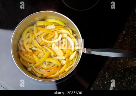 Tranches de pelures d'orange et de citron et placées dans une casserole de l'eau bouillante et du sucre pour faire des peaux confites Banque D'Images