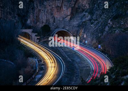 Longue exposition sur une autoroute qui va dans certains tunnels, laissant les faisceaux de lumière sur les véhicules sur la route. Banque D'Images