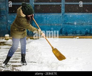 Une femme qui nettoie la neige dans l'arrière-cour Banque D'Images