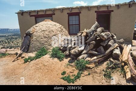 Une grande pile de bois de chauffage se trouve à côté d'un horno, le nom espagnol des fours extérieurs en forme de ruche faits de boue d'adobe qui sont utilisés pour cuisiner dans l'Acoma Pueblo, une communauté amérindienne sur une réserve indienne à l'ouest d'Albuquerque, Nouveau-Mexique, États-Unis. Fondée au XIIe siècle au sommet d'une Mesa en grès éloignée, Acoma est l'une des plus anciennes colonies habitées en permanence en Amérique du Nord. Comme dans les premiers temps, le bois est brûlé à l'intérieur de ces fours traditionnels jusqu'à ce qu'une certaine température soit atteinte pour l'article spécifique cuit, comme le pain, la viande ou le maïs sur l'épi. Banque D'Images