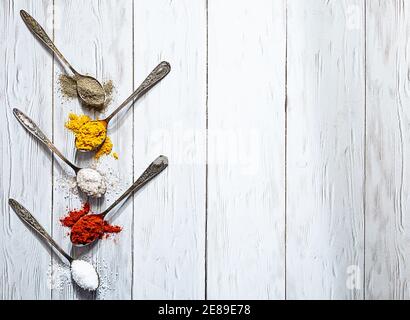 Différentes épices en cuillères vintage. Sel, curry, curcuma, poivre moulu, paprika moulu plat sur une table en bois clair Banque D'Images