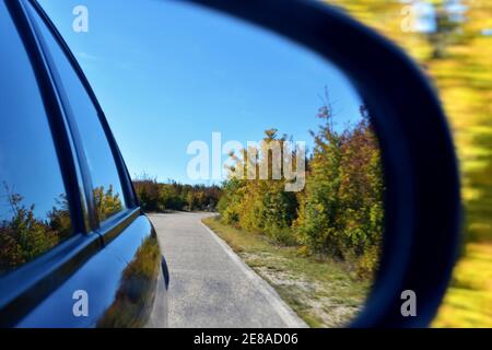 vue du rétroviseur extérieur, le rétroviseur reflète la route, la nature avec des collines vertes et un ciel bleu avec des nuages Banque D'Images