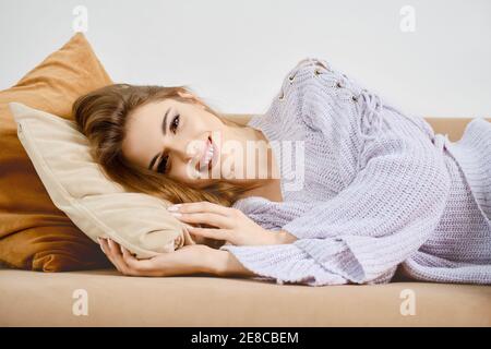 Belle jeune femme posée sur un canapé à la maison Banque D'Images