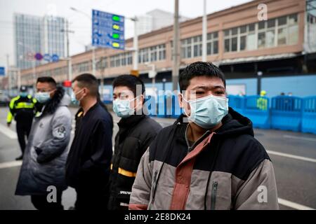 Le personnel de sécurité se protège à l'extérieur du marché des produits de la mer de Huanan lors de la visite de l'équipe de l'Organisation mondiale de la santé (OMS) chargée d'enquêter sur les origines de la coronavirus (COVID-19), à Wuhan, province de Hubei, Chine le 31 janvier 2021. REUTERS/Thomas Peter