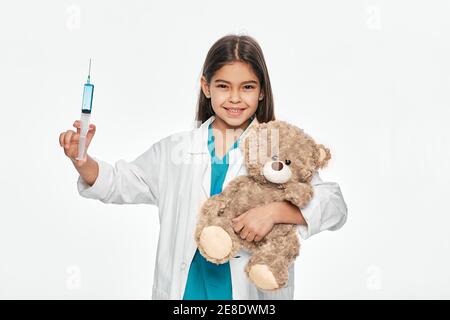 Latino fille américaine va l'injection à son patient jouet d'ours. Enfant jouant médecin vétérinaire, profession future Banque D'Images