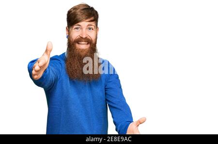 Jeune homme irlandais à tête rouge portant des vêtements décontractés regardant la caméra souriant avec les bras ouverts pour le câlin. Expression gaie embrassant le bonheur. Banque D'Images