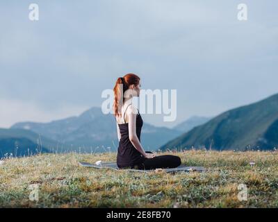 Une femme mince est engagée dans le yoga dans la nature Les montagnes avec des leggings et un t-shirt Banque D'Images