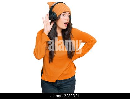 Belle brunette jeune femme écoutant de la musique en utilisant des écouteurs souriant avec la main sur l'oreille écoutant une audition de rumeurs ou de potins. La surdité confond Banque D'Images