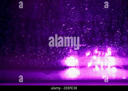 Lumière violette et gouttes de pluie accumulées sur la fenêtre. Banque D'Images