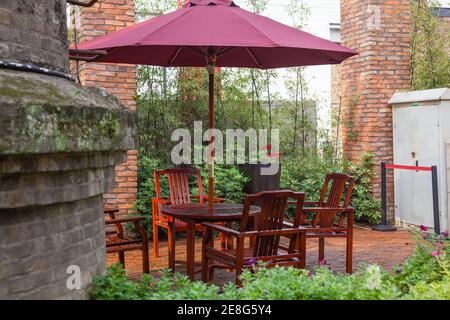 Patio d'été avec tables et chaises en bois sous parapluie dans jardin Banque D'Images