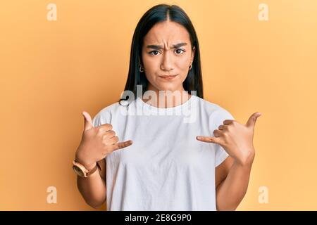 Une jeune femme asiatique faisant le signe du shaka avec les mains sceptique et nerveux, frognant contrarié à cause du problème. Personne négative. Banque D'Images