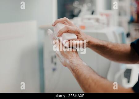 Vue de côté de récolte d'un médecin masculin méconnaissable se désinfecte les mains à l'intérieur hôpital Banque D'Images