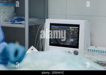 Culture vétérinaire anonyme en gants stériles animaux d'exploitation près d'EKG moniteur de test dans l'hôpital Banque D'Images