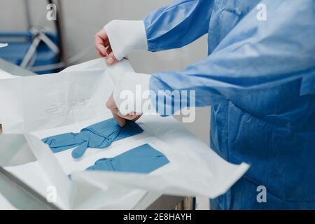 Vue de récolte de jeune vétérinaire anonyme de sexe masculin en uniforme stérile porter des gants élastiques lors de la préparation de la chirurgie en fonctionnement chambre Banque D'Images