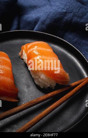 Composition avec vue de dessus de délicieux sushis frais et baguettes de bambou servi sur un plateau noir sur un chiffon à carreaux Banque D'Images