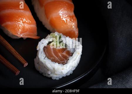 Composition avec vue de dessus de délicieux sushis frais et baguettes de bambou servi sur un plateau noir sur un chiffon à carreaux Banque D'Images