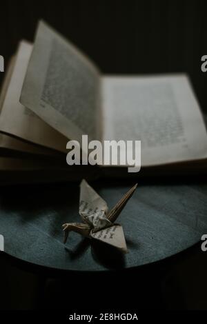 L'origami en papier représente l'oiseau près du manuel sur une table en bois Banque D'Images