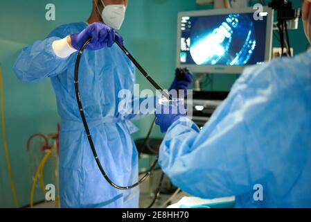 Crop médecin méconnaissable dans la robe chirurgicale et le masque pendant l'endoscope dans l'eau lors de la préparation de la procédure avec un collègue en marche chambre Banque D'Images