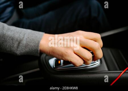 De dessus de la récolte mâle non reconnaissable dans les vêtements décontractés avec main sur le rapport automatique conduisant une voiture moderne Banque D'Images