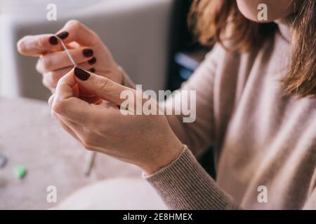 Crop anonyme femme en tenue décontractée fil aiguille pour couture travaillez assis à une table dans un studio lumineux Banque D'Images