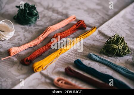 Collection de fils mouline multicolores assortis disposés sur une nappe blanche pour le travail de broderie dans une pièce lumineuse Banque D'Images