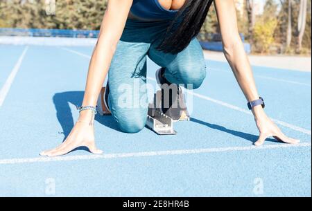 Sportswoman debout dans les blocs de départ en position de départ crouch pendant l'entraînement au stade en été Banque D'Images