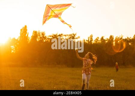 Deux enfants font un cerf-volant au coucher du soleil dans le parc Banque D'Images
