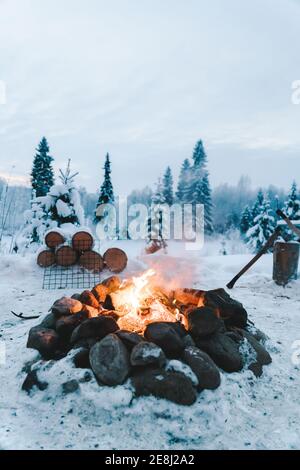 Feu brûlant parmi les pierres et les conifères surcultivés dans les bois en hiver Banque D'Images