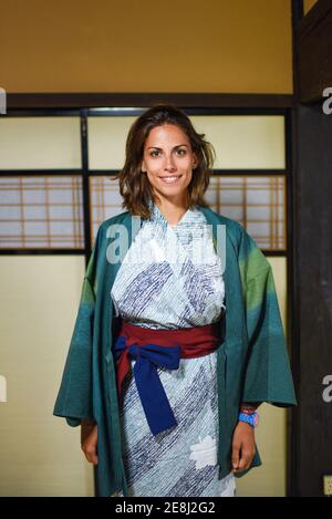 Portrait intérieur de genoux heureux jeune femme caucasienne attrayante portant un kimono japonais traditionnel à l'intérieur d'une maison, Ainokura, Japon Banque D'Images