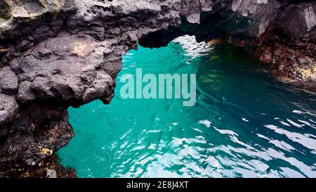 Pont de roche de lave au-dessus de l'eau de mer turquoise, Puerto Egas, baie James, île de Santiago, Galapagos, Equateur Banque D'Images