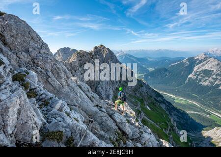 Le alpiniste monte sur une route fixe sécurisée, Mittenwalder Hoehenweg, vue sur la vallée de l'Isar près de Mittenwald, les montagnes du Karwendel, Mittenwald Banque D'Images