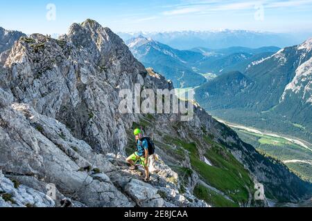 Le alpiniste monte sur une route fixe sécurisée, Mittenwalder Hoehenweg, vue sur la vallée de l'Isar près de Mittenwald, les montagnes du Karwendel, Mittenwald Banque D'Images